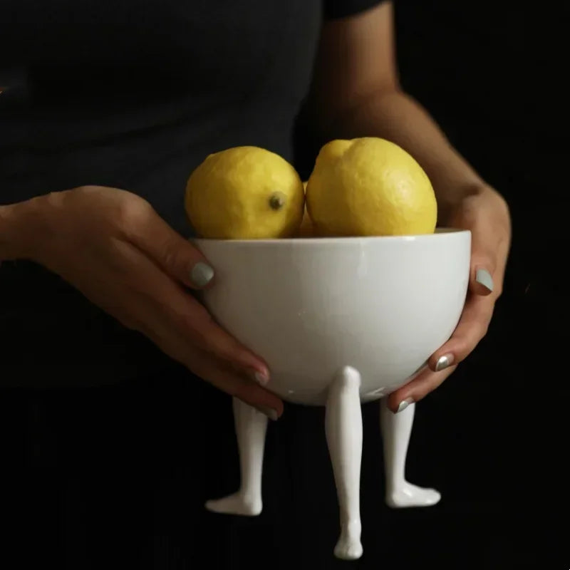 Add a modern touch to your decor with this ceramic fruit bowl featuring abstract human legs. Perfect for storing fruits, jewelry, or small items stylishly and practically.