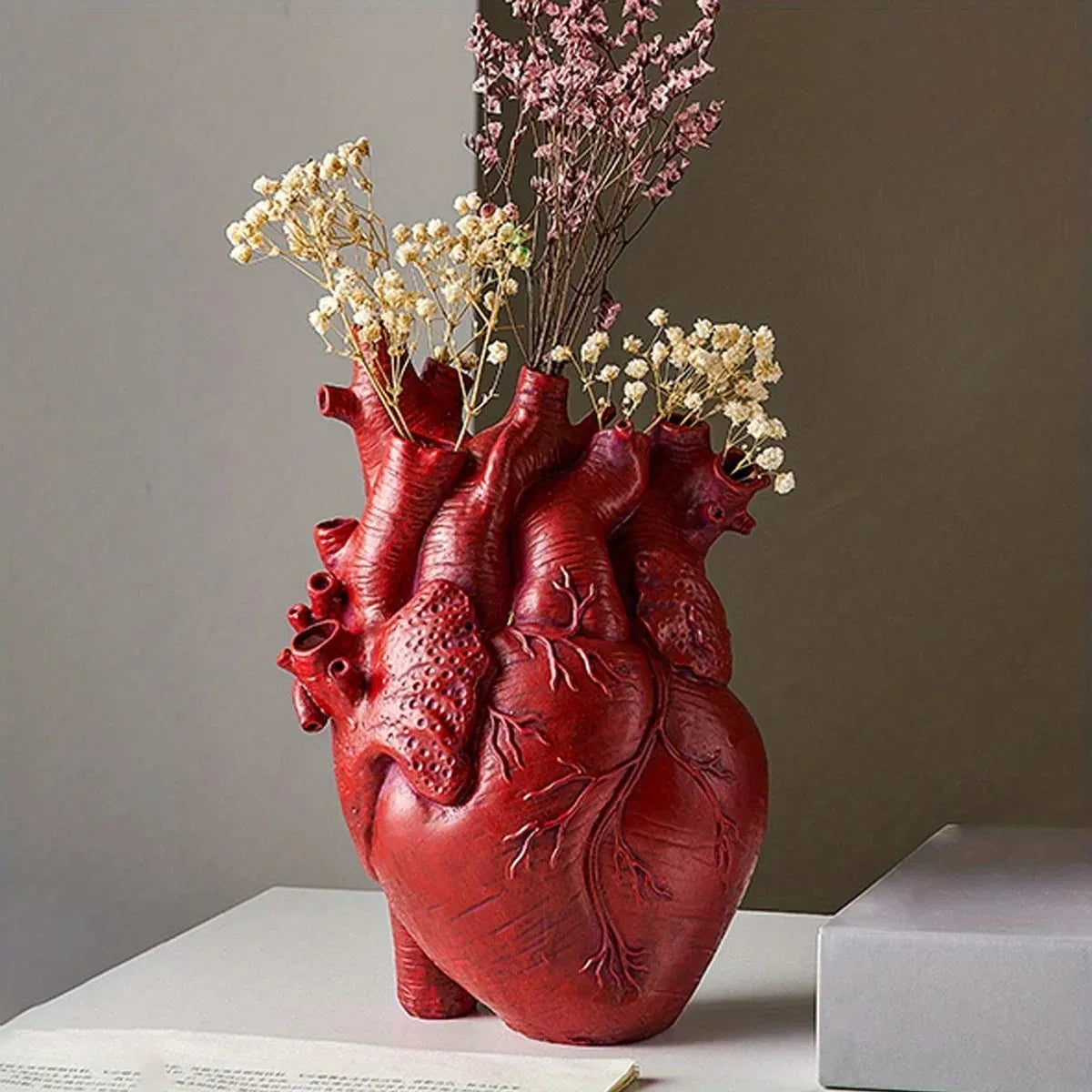 The Resin Heart-Shaped Vase is a unique decor piece, accurately representing a human heart. Durable resin, perfect gift for medical enthusiasts, adds intrigue to any room.